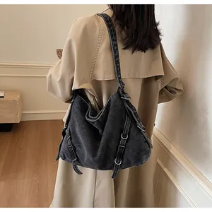Detail of a large capacity denim shoulder bag with metal rings and adjustable straps
