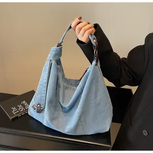 Close-up of light blue denim hobo bag with contrast brown leather buckle and texture