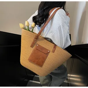 Détail du grand sac cabas en paille avec poche en cuir marron et rivets métalliques argentés
