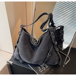 Detail view of washed denim hobo bag featuring vintage metal ring buckles and woven straps