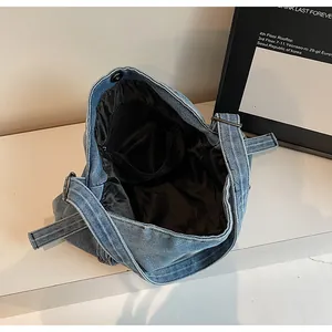 Macro view of denim tote bag interior showing black lining and metal magnetic buckle