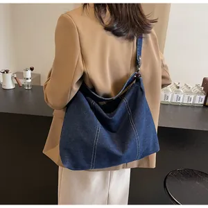 Detail of vintage blue denim hobo bag with contrast stitching on model in a cafe setting
