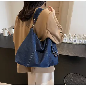 Detail of blue denim tote bag with contrast white stitching and leather accents