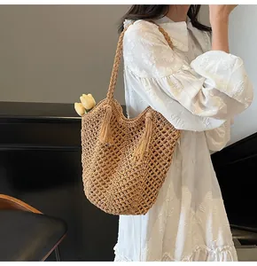 Close-up of handmade straw tote bag featuring mesh knit patterns and tassel details