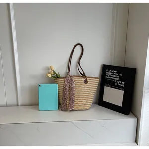 Détail du sac cabas en paille tressée avec lanières en PU brun, foulard et fleurs intérieures