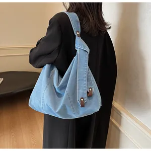 Detail of light blue denim tote with brown leather accents and stylish knotted shoulder strap