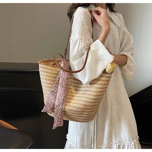 Détail d'un grand sac cabas en paille avec lanières en cuir marron et foulard en soie décoré