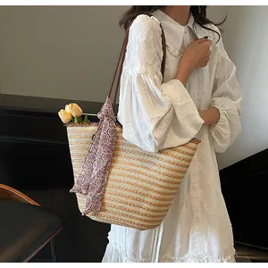 Détail d'un grand sac cabas en paille avec texture tissée et foulard décoratif à motifs