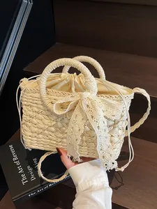 Strohhandtasche in Off-White mit Spitzenbogen und Kordelzug auf Holzgrund