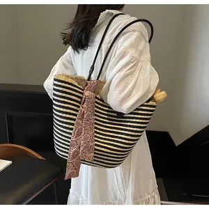 Détail d'un sac cabas en paille tissée à rayures noires et blanches et foulard décoré