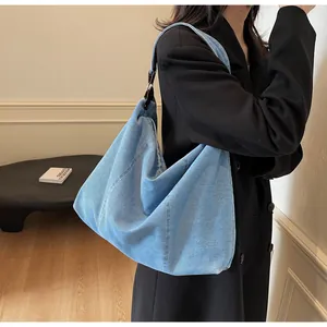 Detail of light blue denim hobo bag featuring vertical stitching and metal hardware