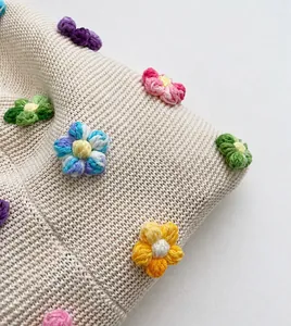 Nahaufnahme von handgestricktem Stoff mit bunten 3D-Häkelblumen-Verzierungen am Tasche