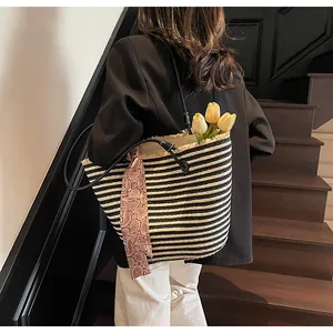 Détail d'un cabas tressé rayé avec bords effilochés et foulard décoratif en soie