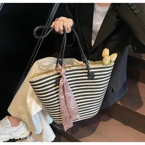 Détail d'un grand cabas tissé à rayures noires et blanches avec un foulard décoratif brun