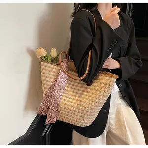 Détail d'un sac cabas en paille tissé avec bandoulière en cuir brun et foulard cachemire