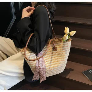 Gros plan sur un sac cabas en paille tissée avec franges et foulard sur l'anse en cuir