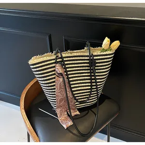 Détail du sac cabas rayé en paille avec bords effilochés et foulard en soie paisley