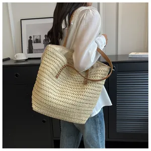 Détail d'un grand sac cabas en paille avec fines anses en cuir marron pour plage et été