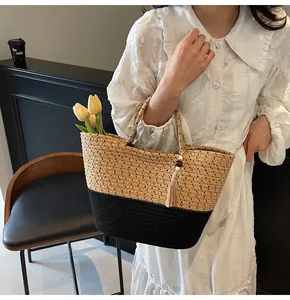 Detail of woven straw tote bag with black contrast trim and decorative wood bead tassel