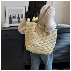 Détail du grand sac cabas en paille avec des anses en similicuir marron et des coutures renforcées