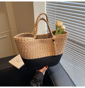 Detail of woven cotton rope tote bag in two-tone beige and black with tassel and wooden bead