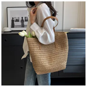 Détail du grand sac cabas en paille avec anses en cuir et fermeture à glissière dorée