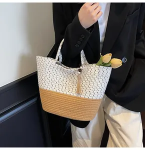 Detail of woven bicolor cotton tote bag with tassel pendant held by model in city style