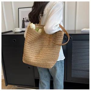 Détail du sac cabas en paille tissée avec bandoulières en cuir marron et texture naturelle