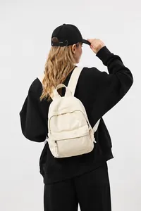 Detailweergave van een minimalistische crème canvas mini-rugzak gedragen door een model in studio