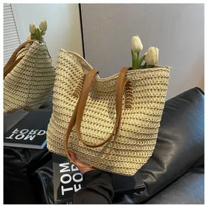 Gros plan détaillé du sac cabas en paille tressée beige avec anses en cuir marron
