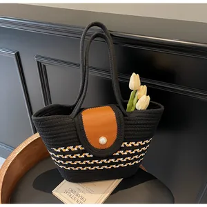Close-up of woven handbag with leather flap, pearl button, and striped base design