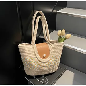 Detail of woven tote bag featuring a pearl button closure and leather flap detail