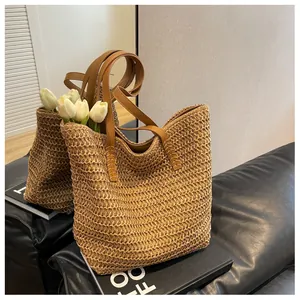 Détail du sac cabas en paille tissé main montrant les poignées en cuir et coutures