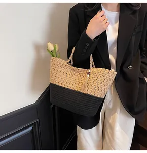 Detail of woven tote bag with beige and black contrast panels and wooden bead tassel