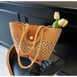Detail of striped woven tote bag with leather flap and pearl clasp on wooden chair