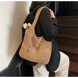 Detail of woven straw tote bag with cutout flower patterns and large shoulder strap