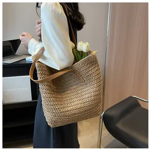 Détail d'un grand sac cabas en paille avec bandoulières en cuir marron et fermeture éclair