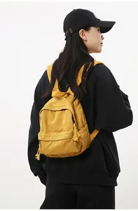Detail van de gele canvas rugzak met ritsvak en kwastje op een zwarte hoodie voor een contrast
