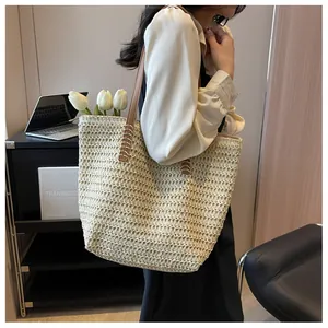 Détail d'un sac cabas en paille avec bandoulières en cuir marron et grande contenance