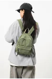 Olijfgroene canvas mini rugzak op model toont casual stijl en een compacte pasvorm aan