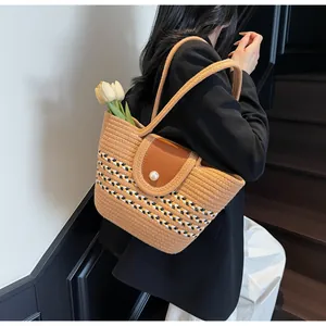 Detail of woven straw bag with striped pattern, leather flap and pearl buckle decoration
