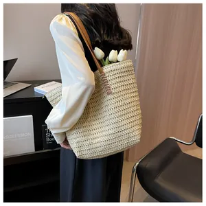 Détail du sac cabas en paille avec bandoulière en cuir brun et texture tressée