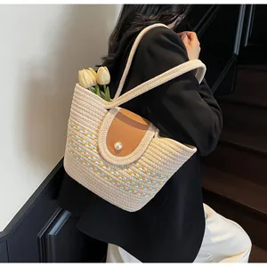 Detail of woven straw tote bag featuring blue-yellow stripes and a pearl buckle closure