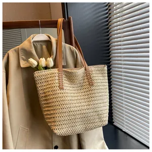 Gros plan du sac en paille tressée avec anses en cuir et tulipes blanches à l'intérieur