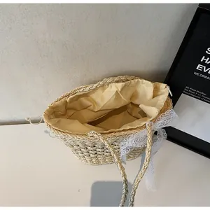 Détail du sac en paille avec nœud en dentelle blanche et doublure jaune à cordon