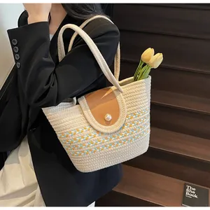 Close-up of woven straw bag with pearl clasp and leather flap on wooden stairs