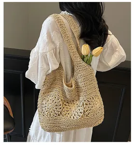 Detail of hand-woven straw tote bag with intricate floral cutouts and textured shoulder strap