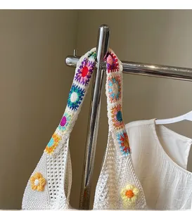 Dettaglio borsa tote in maglia bianca con motivi floreali colorati all'uncinetto sui manici