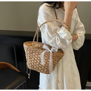 Détail du sac seau en paille tissée avec nœud en dentelle blanche et doublure
