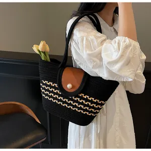 Detail of hand-woven black bag with pearl clasp and stylish brown leather flap
